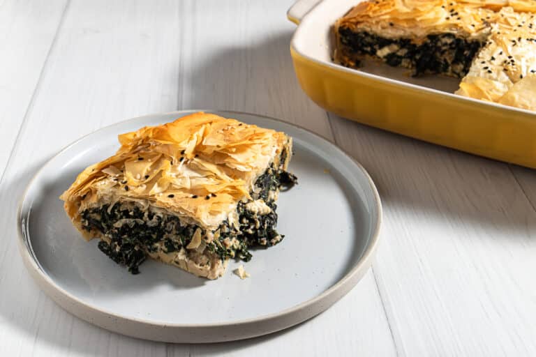 silverbeet and mushroom pie on a plate with the rest of the pie in the background