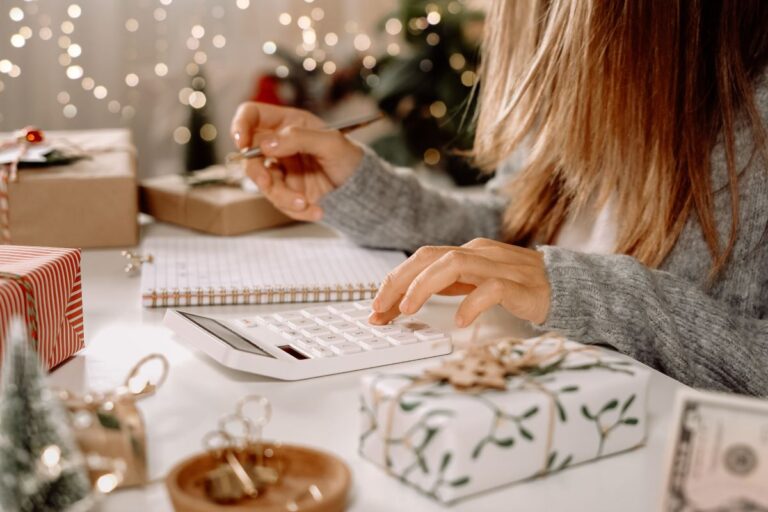 girl doing costing and budget for Christmas with calculator, surrounded by gifts