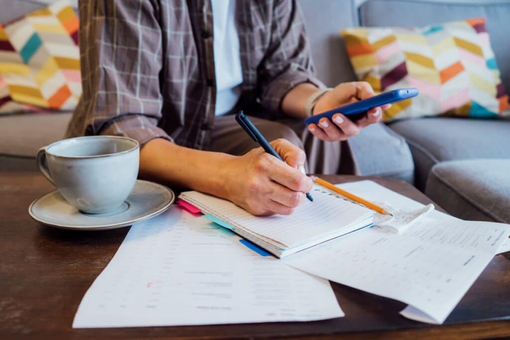 man working out his budget at his coffee table, tea beside him