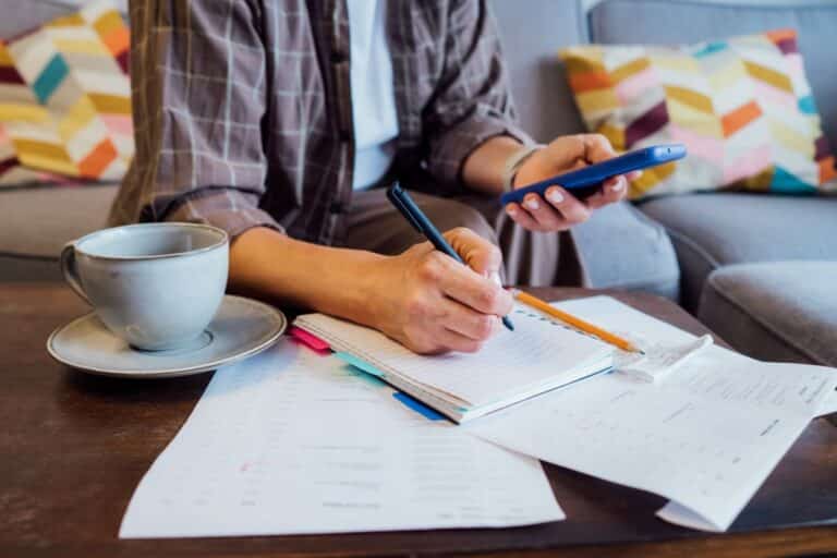 man working out his budget at his coffee table, tea beside him