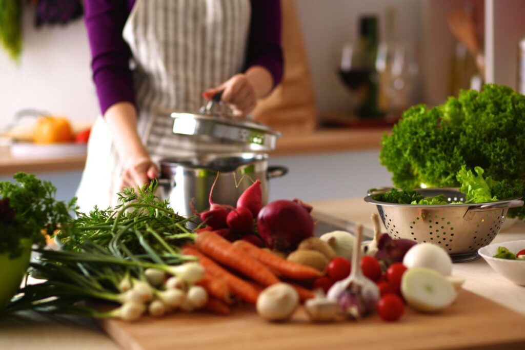 woman cooking in the kitchen surrounded by vegetables
