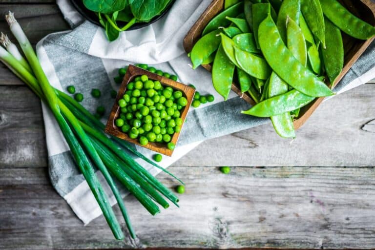flat lay of green spring produce, peas, snow peas, spring onions