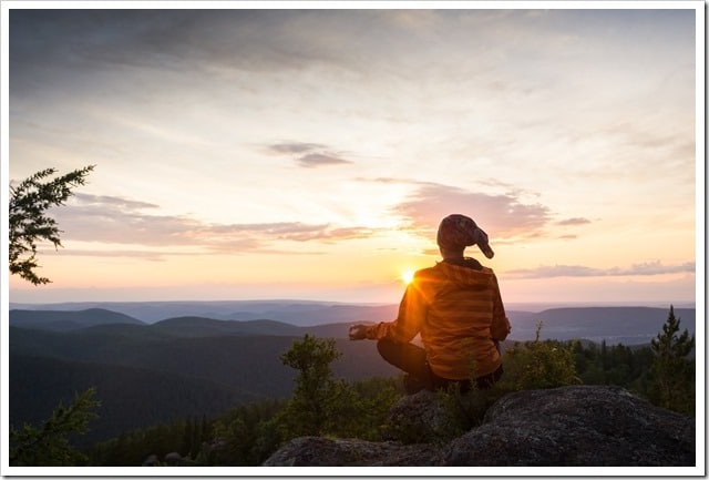 man meditating on a rock