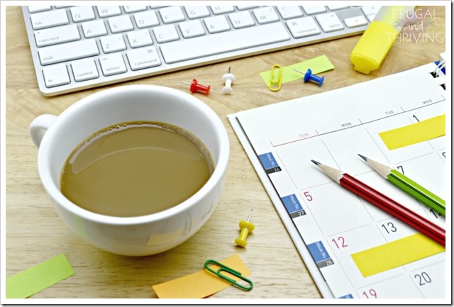 Coffee cup, diary, sticky notes, pencil, pin, clip and keyboard on wooden table