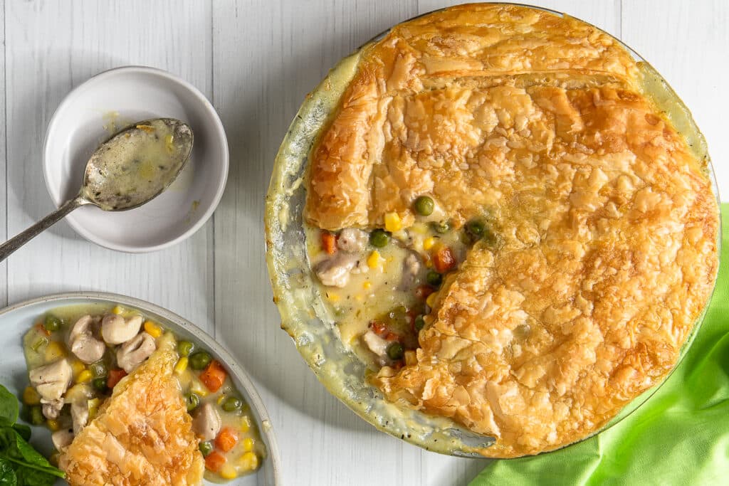 chicken pie in a pie dish with a piece of pie on a plate besides