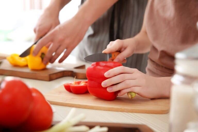 adult teaching child to cut a capsicum