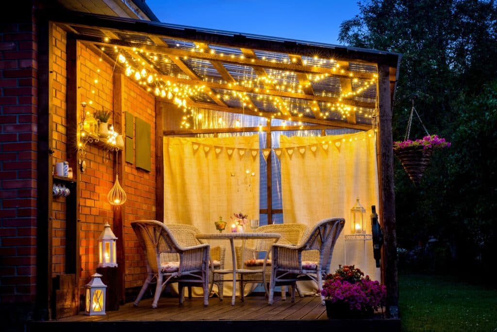 patio at night with fairy lights, candles, and flowers on a table
