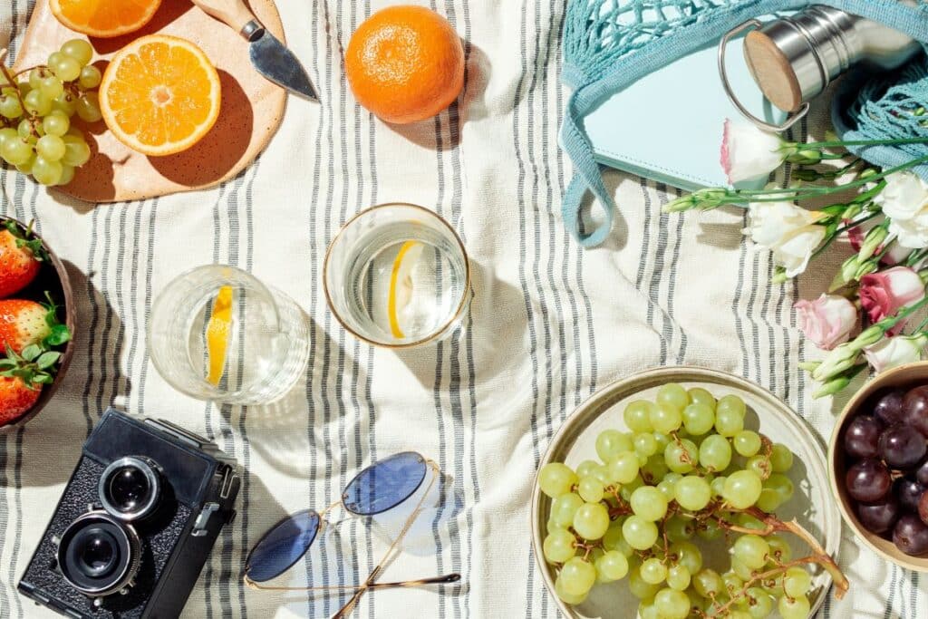 picnic flatlay with fresh fruit, water, camera
