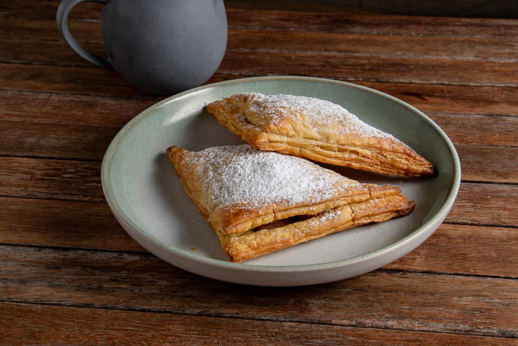 apple turnovers on a plate with a coffee cup in the background