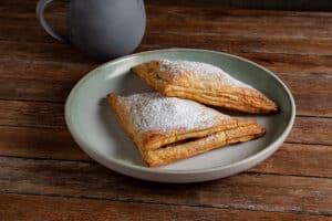 apple turnovers on a plate with a coffee cup in the background