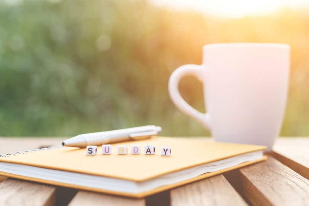 image of coffee and journal with blocks that spell sunday in morning light