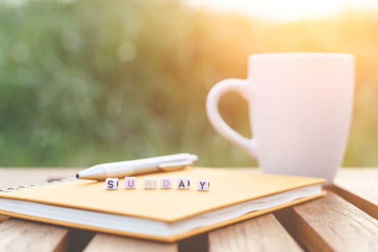 image of coffee and journal with blocks that spell sunday in morning light