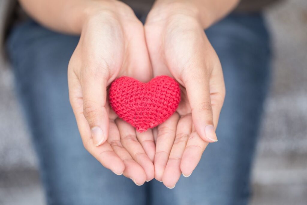 woman holding crocheted heart in hands as a free gift metaphor
