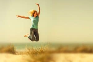 woman jumping in the air at the beach
