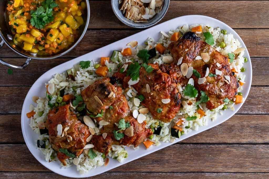 tandoori chicken on a bed of rice pilaf with a mango salsa side and toasted flaked almonds