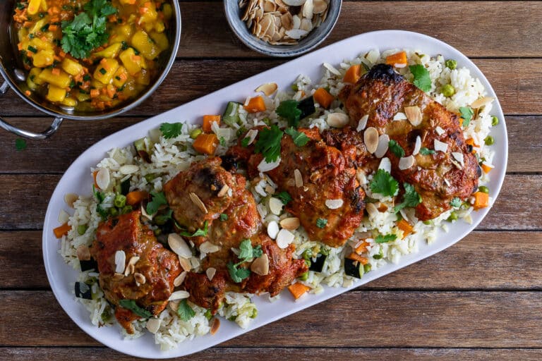 tandoori chicken on a bed of rice pilaf with a mango salsa side and toasted flaked almonds