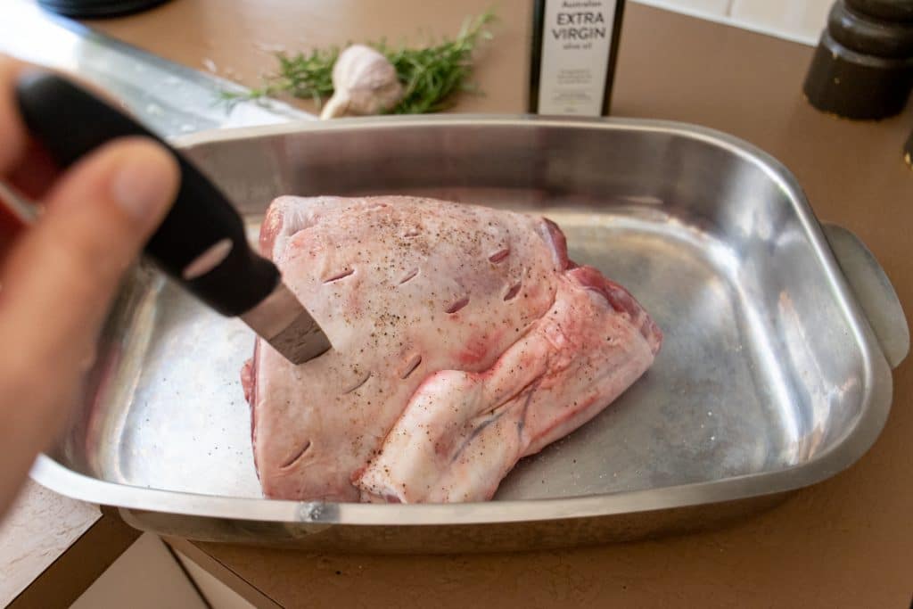 preparing roast lamb leg. cutting slits for garlic and rosemary