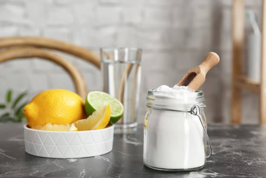 jar of bicarb soda with lemons and limes representing uses for bicarb soda