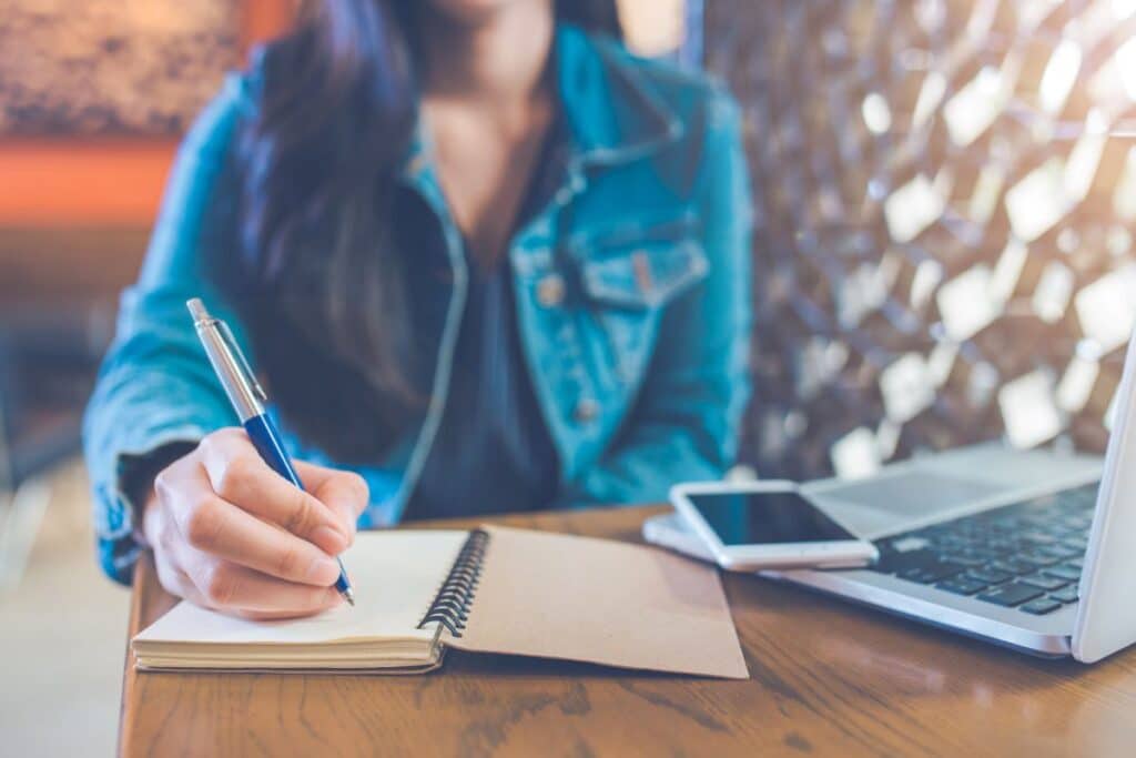 woman making notes with phone representing creating a simple budget