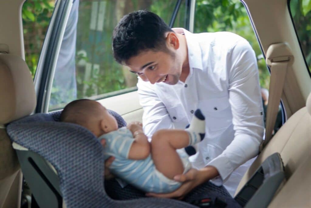 dad putting baby in car seat