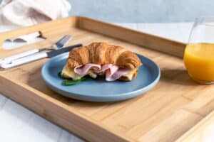 ham and cheese croissant on a tray served with orange juice