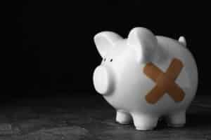 Piggy bank with sticking plasters on grey stone table.