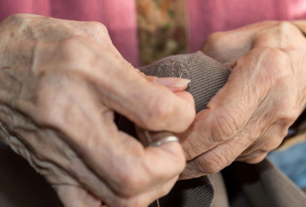 senior hands darning a sock, depression era tips