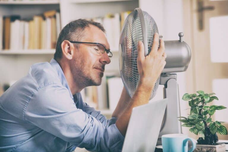 man at work feeling hot in front of fan