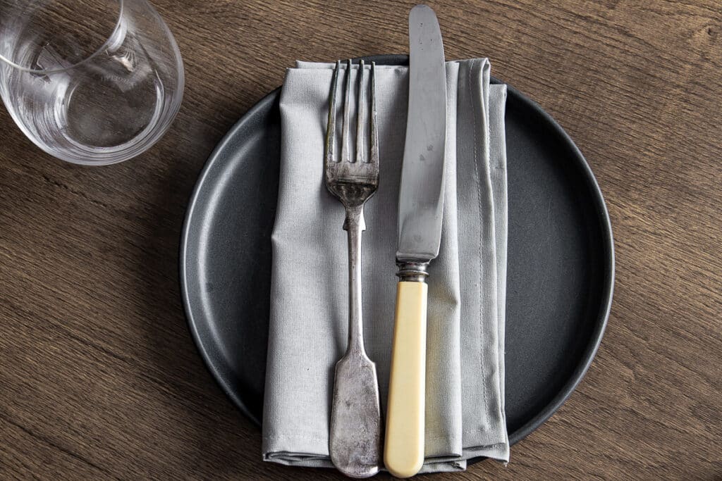 homemade napkin on plate with cutlery and glass