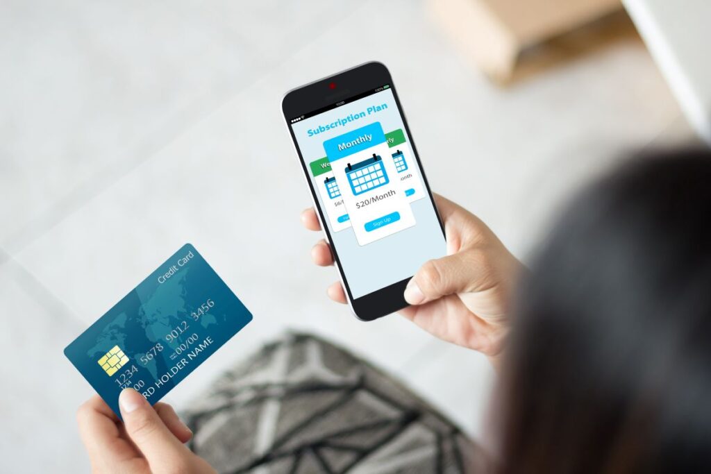 woman holding smartphone and credit card choosing subscription package representing subscription audit