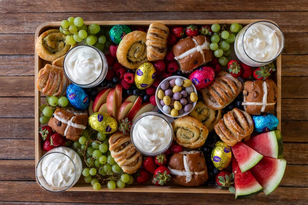 easter grazing board with hot cross buns, fruit, berries, yoghurt, easter chocolate for easter brunch