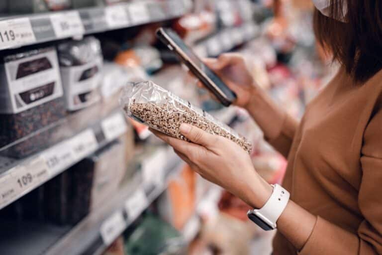 woman using phone to compare unit cost prices on grocery items