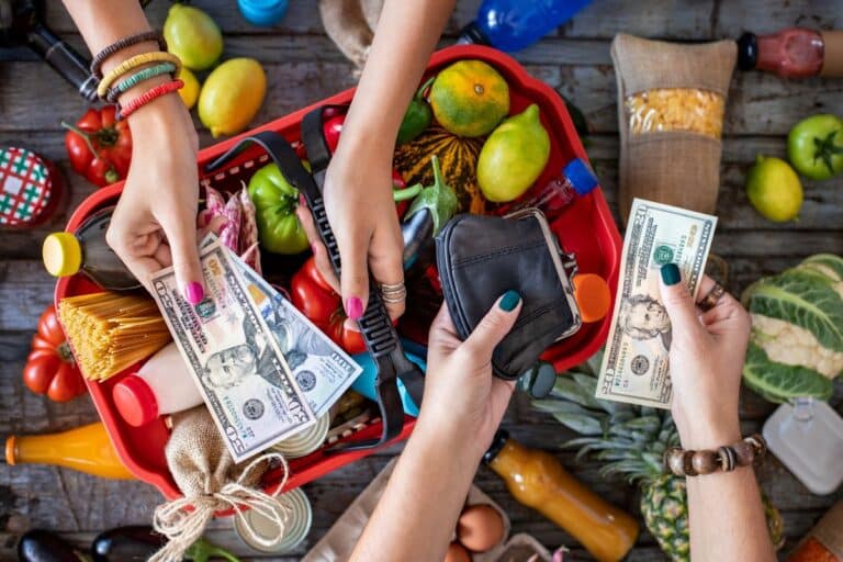 women's hands exchanging money over a basket of groceries