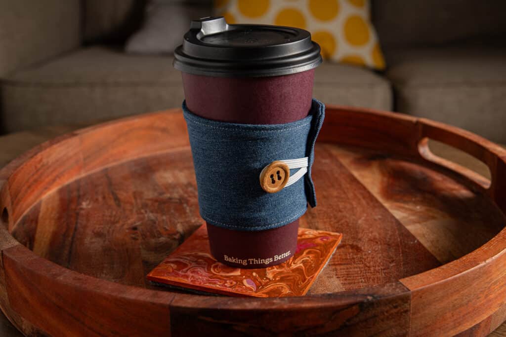 upcycled coffee cup cosy on a takeaway cup that is sitting on a coffee table in a lounge room