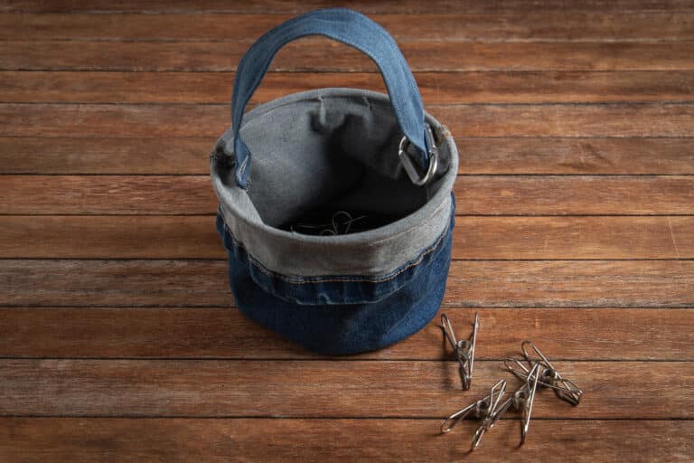 upcycled denim peg bag from old jeans on a wooden background with pegs scattered at the front