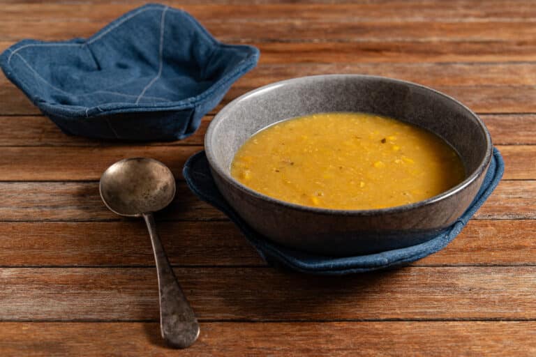 soup in a bowl with an upcycled soup bowl cosy from old jeans and a second cosy in the background with a spoon on a timber background