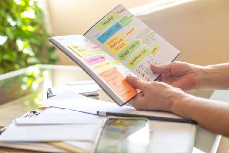 woman holding planner with colourful sticky notes for admin, groceries, household items representing essential life skills